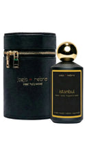 Load image into Gallery viewer, Jojo x Nebria Istanbul home/body fragrance spray bottle next to its black textured cylindrical carrying case with gold zipper and gold lettering, on a white background.