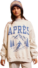 Load image into Gallery viewer, Oversized cream sweatshirt featuring bold blue “APRÈS” lettering and a vintage-inspired ski scene with mountains, pine trees, and a skier graphic on the front.