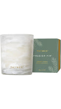 Load image into Gallery viewer, Thymes Frasier Fir aromatic candle in a softly marbled white glass vessel with gold Thymes lettering, displayed beside a sage green box with delicate fir branch illustrations and gold accents.