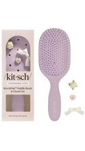 Load image into Gallery viewer, Purple paddle brush with decorative charms next to its packaging on a white background