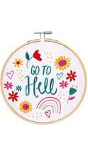 Load image into Gallery viewer, Wooden embroidery hoop featuring white fabric with colorful embroidered flowers, hearts, a rainbow, and whimsical accents surrounding the phrase “Go to Hell” in teal stitching, shown against a clean white background.