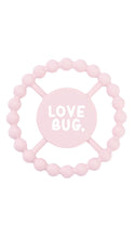 Load image into Gallery viewer, A light pink silicone baby teether with a circular beaded outer ring and a central round piece printed with the words 'LOVE BUG.' in white, shown on a plain white background.