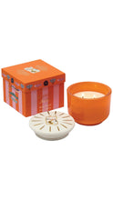 Load image into Gallery viewer, An orange candle featuring an orange glass jar with two lit wicks, a white lid with gold cat illustrations, and an orange striped gift box with character graphics, all on a white background.