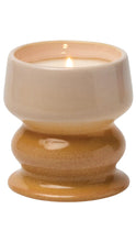 Load image into Gallery viewer, A lit ceramic candle holder with a warm beige upper bowl and a glazed amber-brown base, shown on a plain white background.