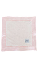 Load image into Gallery viewer, A square baby blanket featuring a soft, textured off-white fleece center surrounded by a light pink satin border, with a small white brand label in the bottom right corner.