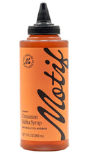 Load image into Gallery viewer, Clear squeeze bottle of Motif Premium Cinnamon Babka Syrup with warm amber-colored syrup, an orange label with bold black lettering, and a black dispensing cap. The 12 fl oz bottle is labeled naturally flavored.
