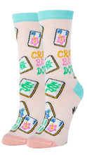 Load image into Gallery viewer, A pair of crew socks with a light pink base featuring a colorful print of mahjong tiles, Chinese characters, and the words 'CRACK BAM DOT' in yellow and green, finished with light blue cuffs and heels and pale pink toes.
