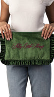 A person holding a green velvet clutch or pouch with ruffled trim and the phrase 'Silly Little Things' embroidered in pink script across the front.