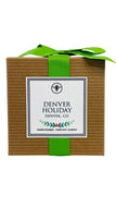 A packaged candle with a label reading 'Denver Holiday', with a green ribbon on top.
