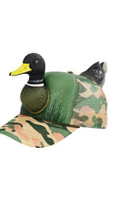 Load image into Gallery viewer, A camouflage trucker hat with a realistic duck head attached to the front and a second duck figure attached to the back, shown on a plain white background.
