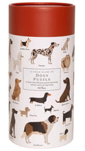 Load image into Gallery viewer, A cylindrical puzzle tin with a terracotta red lid and a white body printed with illustrated dog breeds and the text 'A FIELD GUIDE TO DOGS PUZZLE'.
