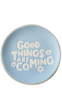 Load image into Gallery viewer, A round light blue ceramic plate with raised white text reading 'Good THINGS ARE COMING' and small white flower motifs, shown on a plain white background.
