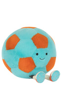 Load image into Gallery viewer, A plush soccer ball toy with a light blue body, orange pentagonal panels, a small embroidered smiley face, and small white-and-blue feet, shown on a plain white background.
