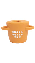Load image into Gallery viewer, An orange silicone snack cup with a lid and side handles, featuring the text 'SNACK SUPER FAN' in white on the front, set against a plain white background.
