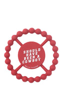 Load image into Gallery viewer, A red silicone dog toy with a circular beaded outer ring and a central red disc featuring the text 'SHOULD HAVE BEEN A COWBOY' and 'BELLA TUNNO' in white, shown on a plain white background.

