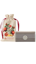 Load image into Gallery viewer, Essências de Portugal bar soap displayed beside a cream drawstring pouch decorated with pomegranates, red blossoms, green leaves, and ginger, finished with deep red ribbon ties and the brand’s crown logo, shown against a clean white background.
