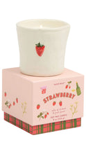 Load image into Gallery viewer, A white ceramic soy wax candle with a red strawberry illustration sits on top of its pink packaging box, which features red and green plaid trim and the text 'STRAWBERRY' and 'PADDYWAX'.
