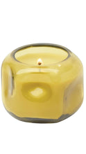 Load image into Gallery viewer, A lit yellow candle in a rounded, translucent glass holder, shown against a plain white background.
