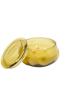 Load image into Gallery viewer, A yellow translucent glass jar candle with its matching lid leaning against it, shown on a plain white background.
