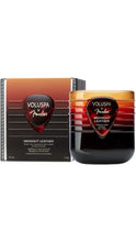 Load image into Gallery viewer, Voluspa x Fender Midnight Leather 11 oz coconut wax candle in a ribbed amber-to-black gradient glass jar with a dark red guitar pick-shaped label, displayed beside its matching gradient box with black trim.

