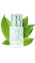 Load image into Gallery viewer, Perfume bottle labeled 'The Blanc' surrounded by green leaves on a white background
