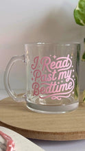 Load image into Gallery viewer, Clear glass mug with pink text 'I Read Past my Bedtime' on a wooden surface.

