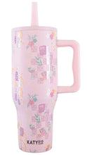 Load image into Gallery viewer, A light pink handled tumbler with a matching pink straw, decorated with a cocktail-themed pattern featuring martini glasses, checkered squares, and floral motifs. The brand name 'KATYDID' is printed in black near the bottom.
