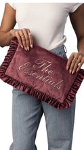 Load image into Gallery viewer, A person wearing a white top and light blue jeans holds a burgundy velvet clutch bag with ruffled edges and the words 'The Essentials' in metallic script.
