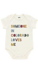 Load image into Gallery viewer, An off-white short-sleeve baby bodysuit featuring the text 'SOMEONE IN COLORADO LOVES ME' printed on the front in a retro, multi-colored font.

