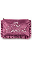 Load image into Gallery viewer, A dusty rose velvet clutch pouch with ruffled trim on the sides and a gold zipper, featuring the text 'The Essentials' in white cursive script on the front.
